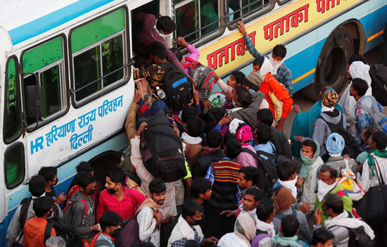 عمال يحاولن ركوب حافلة مزدحمة لعودتهم إلى قراهم بعد إغلاق البلاد فى غازى آباد بالهند