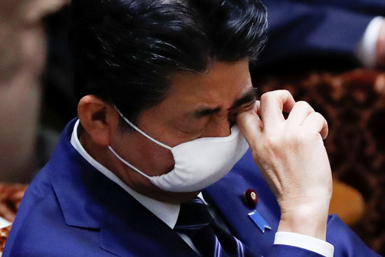 رئيس وزراء اليابان يفرك عينيه من وراء الكمامة