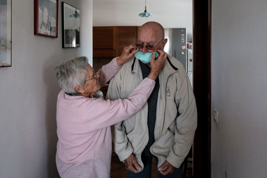 إمرأة تساعد زوجها على إرتداء قناع الوجه فى إيطاليا