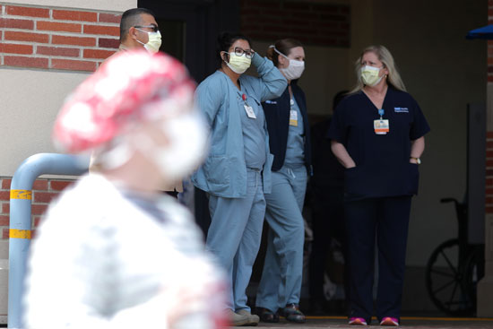 الممرضات يقفن في مدخل المستشفى يراقبن احتجاج الممرضات على معدات الوقاية الشخصية في المركز الطبي بجامعة كاليفورنيا في لوس أنجلوس