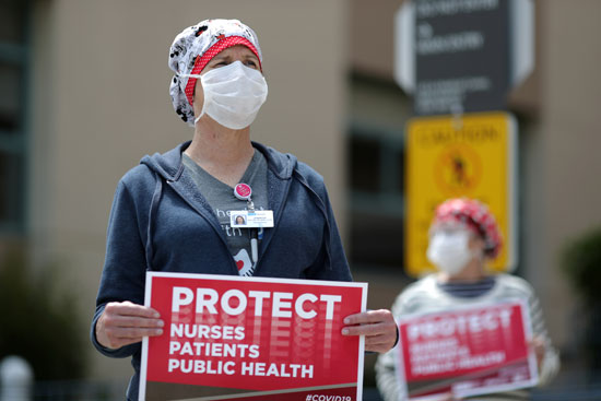 العاملون بالرعاية الصحية يرفعون لافتات أثناء احتجاجهم