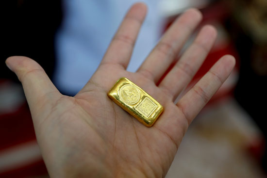 يعرض أحد العملاء قطعة من الذهب للبيع في متجر ذهب