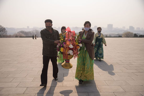 رجل وسيدة يحملان الزهور لوضعها على النصب التذكارى خلال الاحتفالات