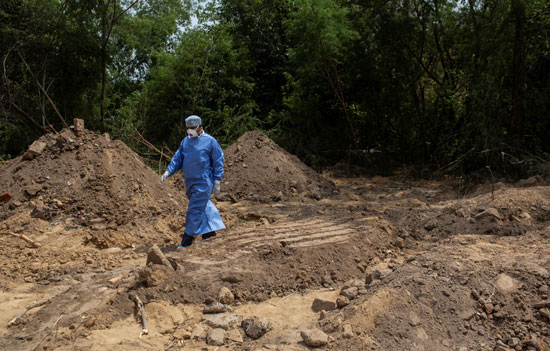 عاملة صحية تمشي قبور الأشخاص الذين ماتوا بسبب  كورونا  في مقبرة في نيودلهي