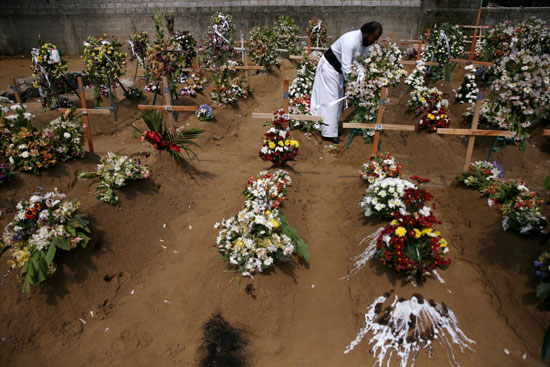 كاهن يرتب الزهور في موقع دفن جماعي