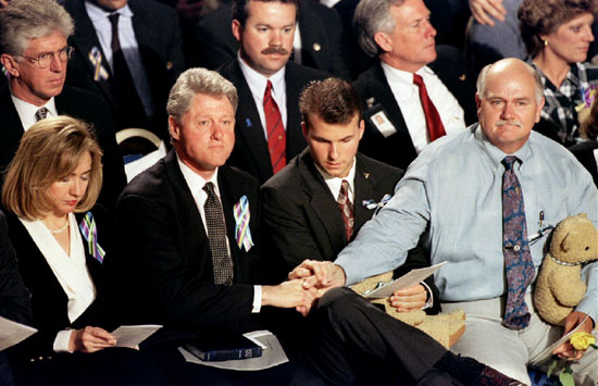 الرئيس الأمريكي الأسبق  بيل كلينتون يمسك بيد زوج إحدى المفقودات فى الحادث خلال صلاة لتكريم ضحايا التفجير
