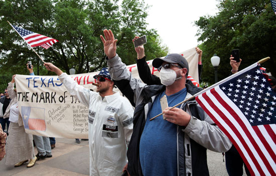 متظاهرون يرتدون الكمامات ويحملون أعلام أمريكا  خلال الوقفة