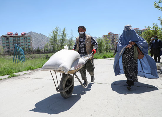 أفغانى وزوجته يتسلم حصته من القمح المجانى