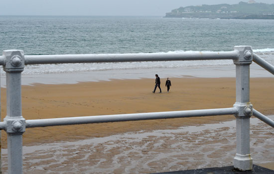 1  امرأة وفتاة يرتديان أقنعة يسيران على طول الشاطئ بعد رفع القيود المفروضة على الأطفال جزئيًا للمرة الأولى في ستة أسابيع