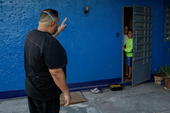 طبيب مستشفى نوجاليس خافيير مارتينيز يلوح لعائلته خارج منزله  قبل العودة إلى العمل ، حيث يمارس الابتعاد الاجتماعي من أجل منع عائلته من الإصابة بمرض كورونا