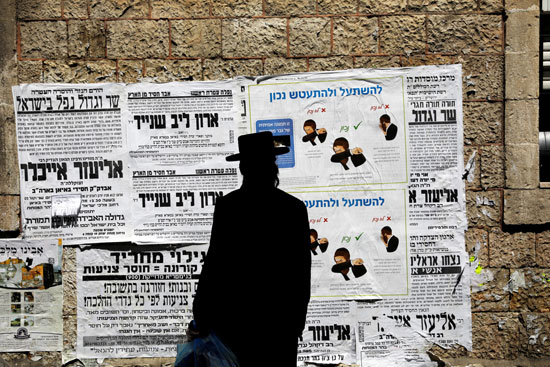رجل-يهودي-أرثوذكسي-ينظر-إلى-لوحة-إعلانية-محلية-تحتوي-على-تعليمات-تم-نقلها-إلى-الفيروس-التاجي-في-شارع-في-الحي-اليهودي-الأرثوذكسي-في-القدس