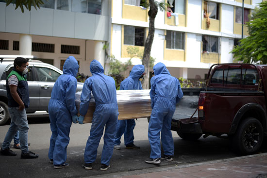 عمال المنازل الجنائزية يقومون بتحميل نعش يحتوي على جسد رجل مات بكورونا