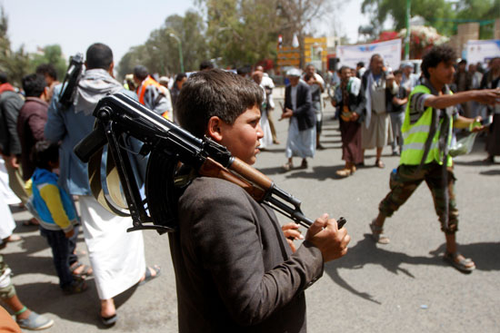 صبي يحمل سلاحًا أثناء رؤيته هو وأنصار الحوثي خلال تجمع في صنعاء