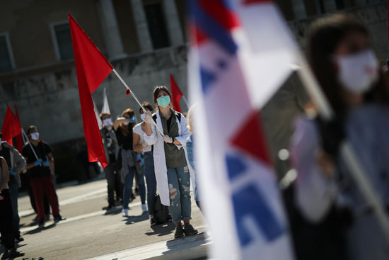 يرتدي أعضاء نقابة PAME النقابية الشيوعية أقنعة واقية أثناء ممارستهم للمسافة الاجتماعية خلال مسيرة للاحتفال بعيد العمال