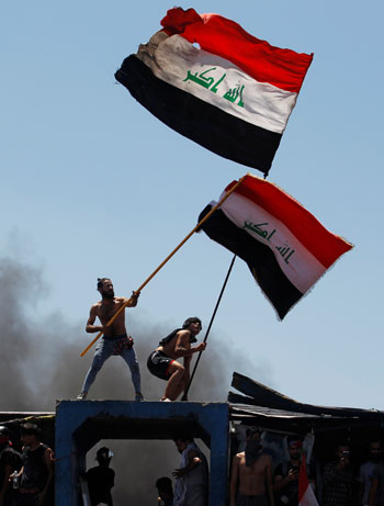 متظاهرون يرفعون أعلام العراق