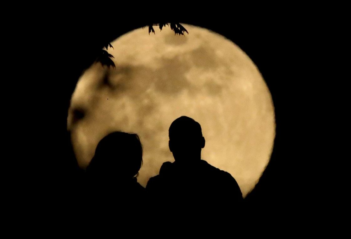 زوجان يجلسان أمام القمر العملاق