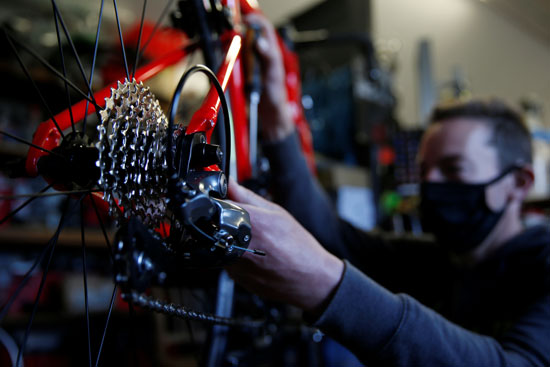 يقوم الدراج والميكانيكي رومان بايلي بإصلاح دراجة في متجر الدراجات الخاص به في ماركوينج ويرتدى كمامة