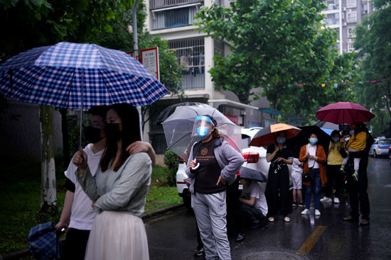 سكان ينتظرون في الطابور لاختبار الحمض النووي وسط هطول الأمطار