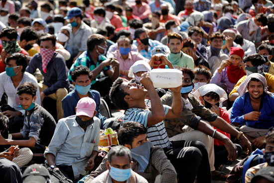 رجل يشرب المياه أثناء انتظارهم العمال المهاجرين