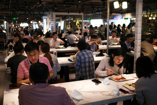 يستمتع الناس بوجبتهم في قاعة الطعام في أحد مراكز التسوق خلال وقت الغداء