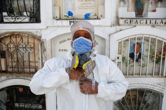 عامل مقبرة يضبط معداته الواقية الشخصية أثناء اعتراض التوابيت