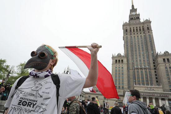 متظاهر يحمل العلم البولندي أثناء استقلال وارسو المناهض للحكومة والحظر
