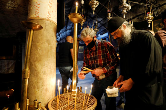 رجال يشعلون الشموع في كنيسة المهد أثناء إعادة فتحها