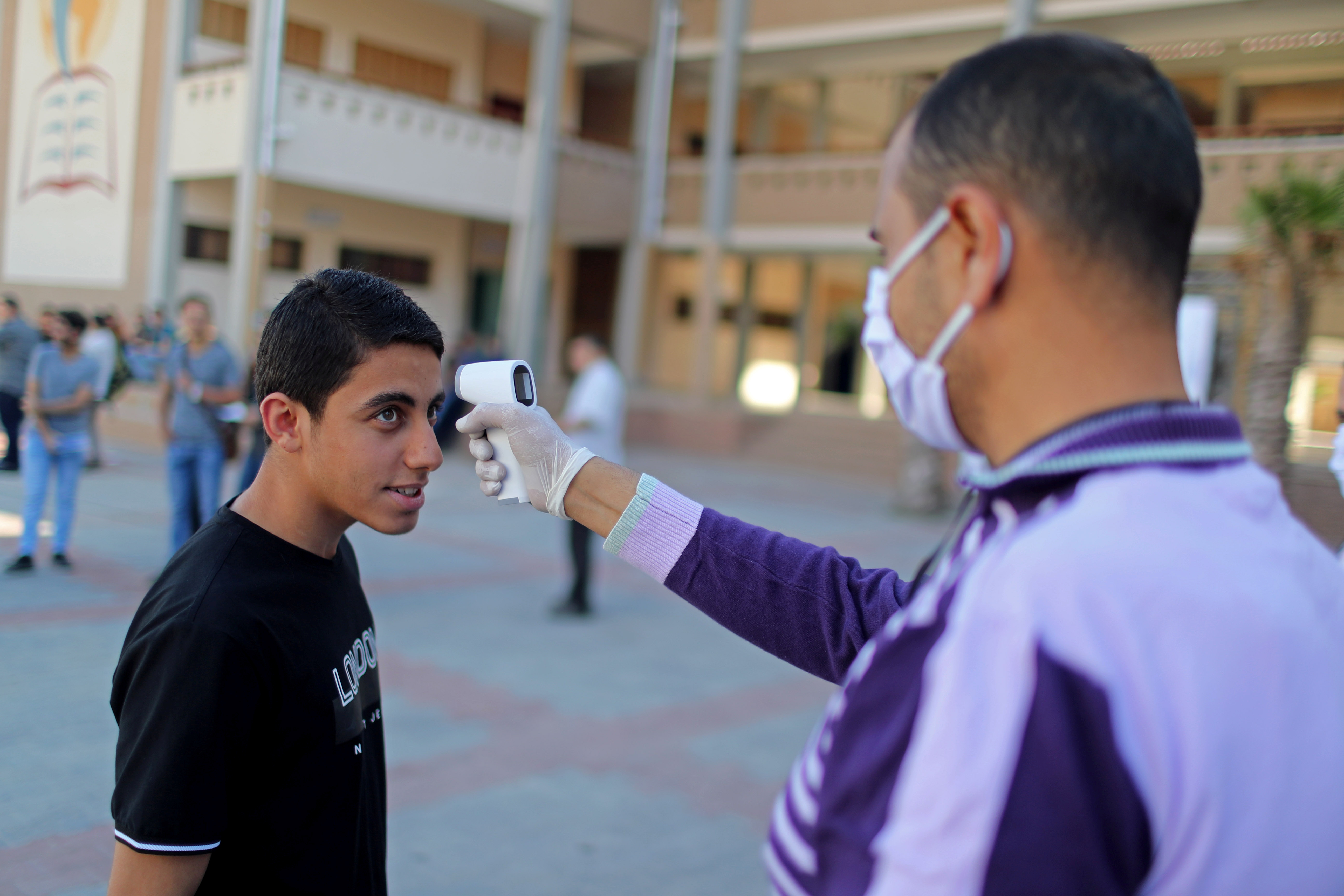 طالب فلسطيني يفحص درجة حرارة جسده لدى وصوله لأداء امتحانات الثانوية العامة