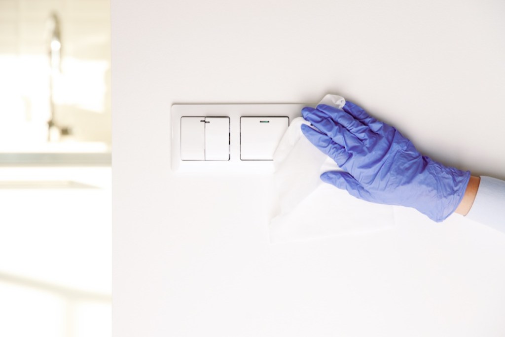 woman-hand-cleaning-light-switch-gloves woman-hand-cleaning-light-switch-gloves