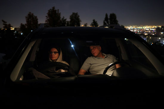 رجل يجلس داخل سيارته بجوار زوجته لمشاهدة الفيلم
