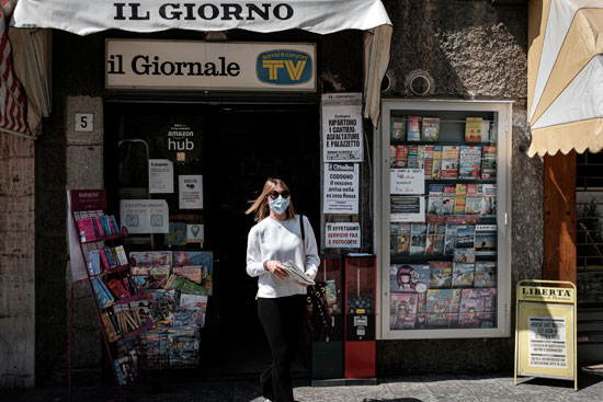 سيدة تخرج من إحدى المكتبات و تحمل جريدة ورقية