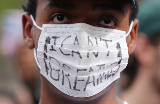أحد المتظاهرين يضع شعارا على الكمامة خلال التظاهرة