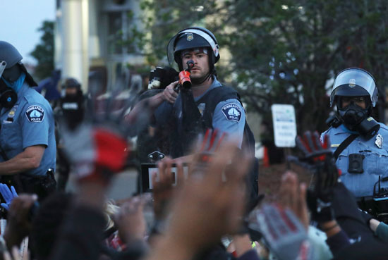 شرطى يوجه سلاحه للمتظاهرين
