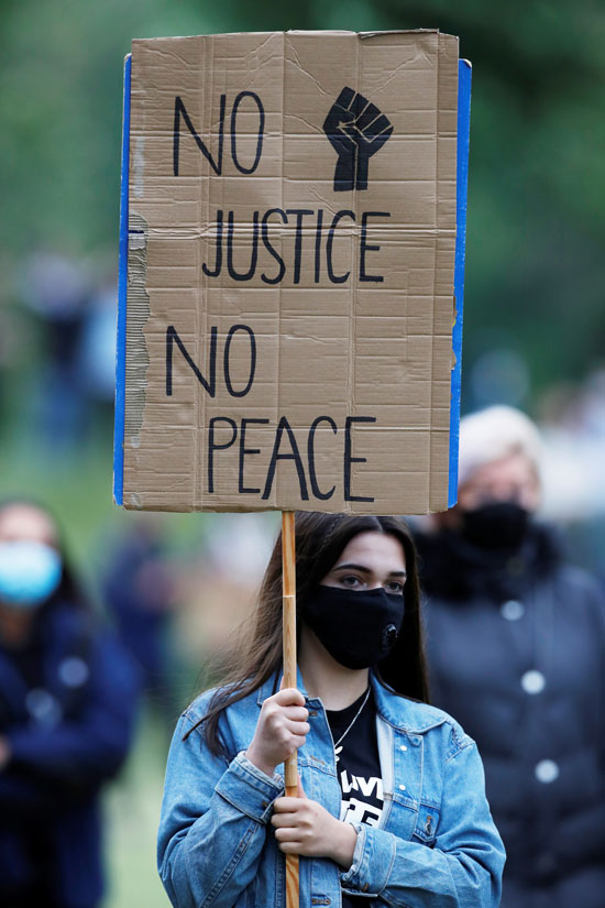 متظاهرة ترفع لافتة تطالب بتطبيق العدالة للوصول للسلام