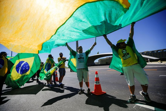 متظاهرون يرفعون علم البرازيل