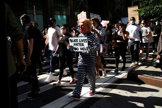 متظاهر يرتدي قناع ترامب وزى حرامي خلال المظاهرة