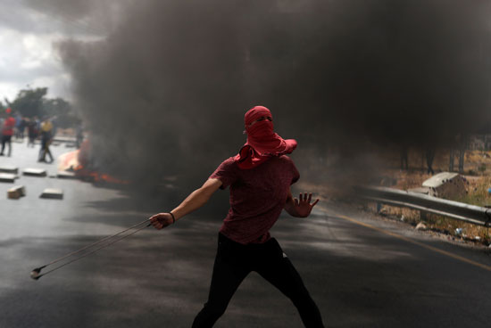 شاب فلسطيني يقذف الاحتلال بالحجارة