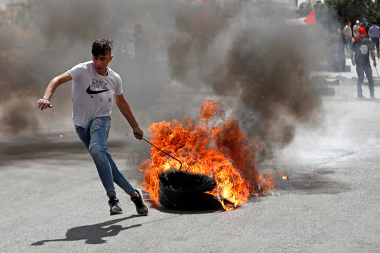 شاب فلسطينى يحرق إطار سيارة