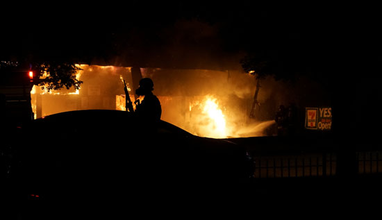 ضابط شرطة يقف خارج أحد المحال المحترقة بولاية سانت لويس