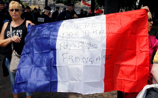 متظاهرون مضادون يحملون علمًا فرنسيًا أثناء احتجاج على إزالة تمثال الجنرال فيدهيربي