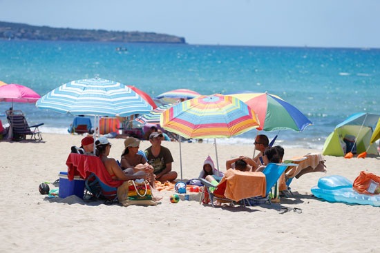 أسرة إسبانية تستمتع بالشمس والبحر بأحد الشواطئ