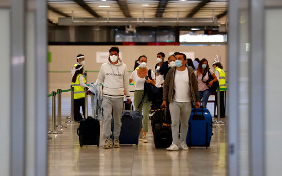 المسافرون يصلون مطارات اسبانيا وعلى وجوههم الكمامات
