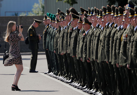 امرأة تلتقط صورًا للخريجين وهم يقفون في الطابور أثناء حصولهم على الدبلومات في الأكاديمية العسكرية في روسيا البيضاء