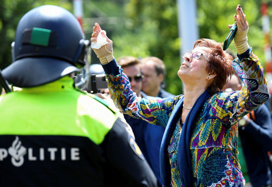 سيدة ترفع يديها أ أثناء مشاركتها في احتجاج ضد تدابير التسبب في فيروس كورونا