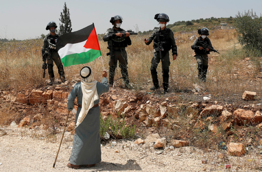 رجل فلسطينى يحمل علم بلاده فى وجه جنود الاحتلال