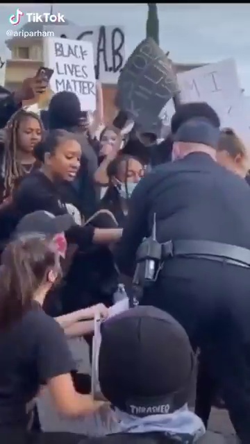 شرطي أمريكي أبيض ينحني لـ حبيبته السمراء وسط المتظاهرين (1)