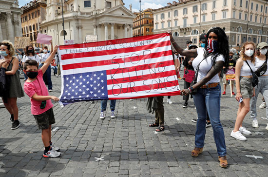 متظاهرون يرفعون علم أمريكا بشعارات ضد العنصرية