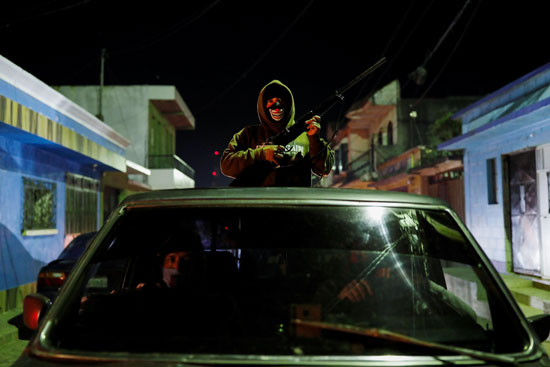 شاب يحمل السلاح على ظهر سيارة