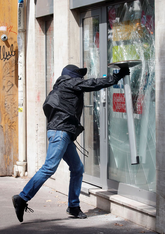 رجل يحطم نافذة متجر في مظاهرات لأفراد السترات الصفراء مع عمال الصحة الفرنسيون