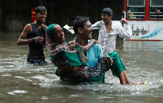 رجل يحمل سيدة مسنة وسط مياه الفيضانات
